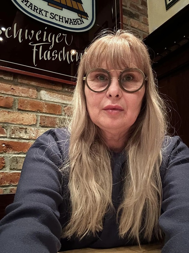 Mariana Pfeiffer, la masa unui restaurant, purtând haine negre și ochelari de vedere cu ramă maro