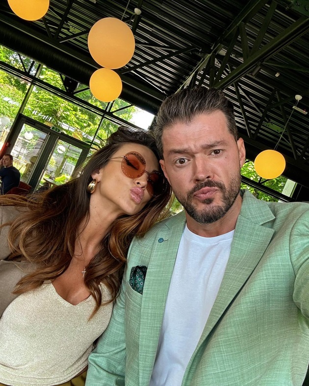 Victor Slav într-un sacou verde, la masa unui restaurant, alături de partenera lui, Selina, îmbrăcată în nuanțe de bej și maro