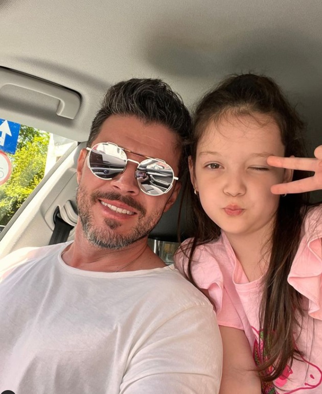 Victor Slav în mașină, cu ochelarii de soare pe ochi, alături de fiica lui, care este așezată pe bancheta din spate și s-a apropiat se el pentru a face o poză