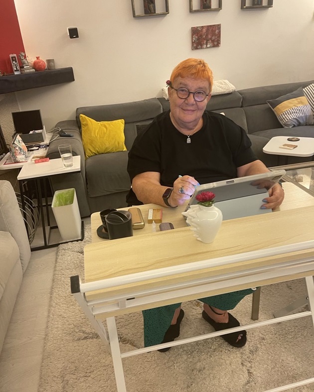 Ruxandra Ion sând la masa de lucru, cu tableta în față și cu ochelarii la ochi