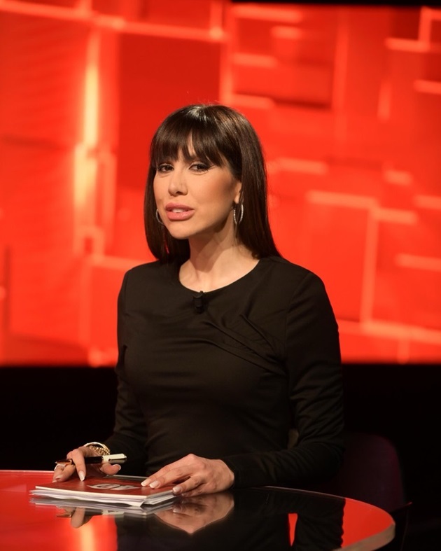 Denise Rifai la pupitrul emisiunii „40 de întrebări cu Denise Rifai” de la Kanal D, îmbrăcată în negru, ținând mâinile pe fișele cu întrebări