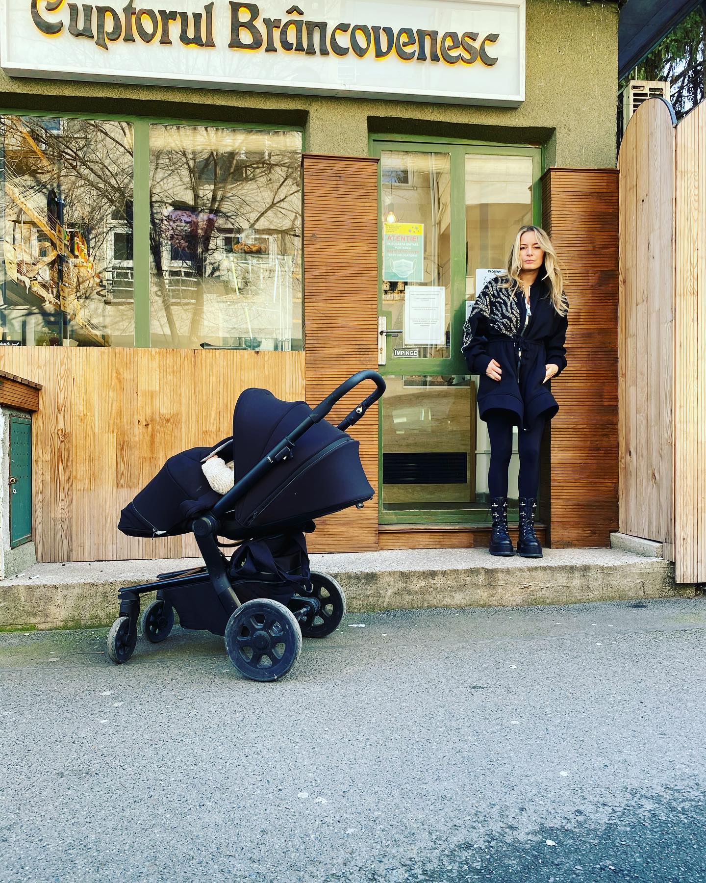 Laura Cosoi în fața brutăriei sale, alături de una dintre fetițele ei care stătea în cărucior