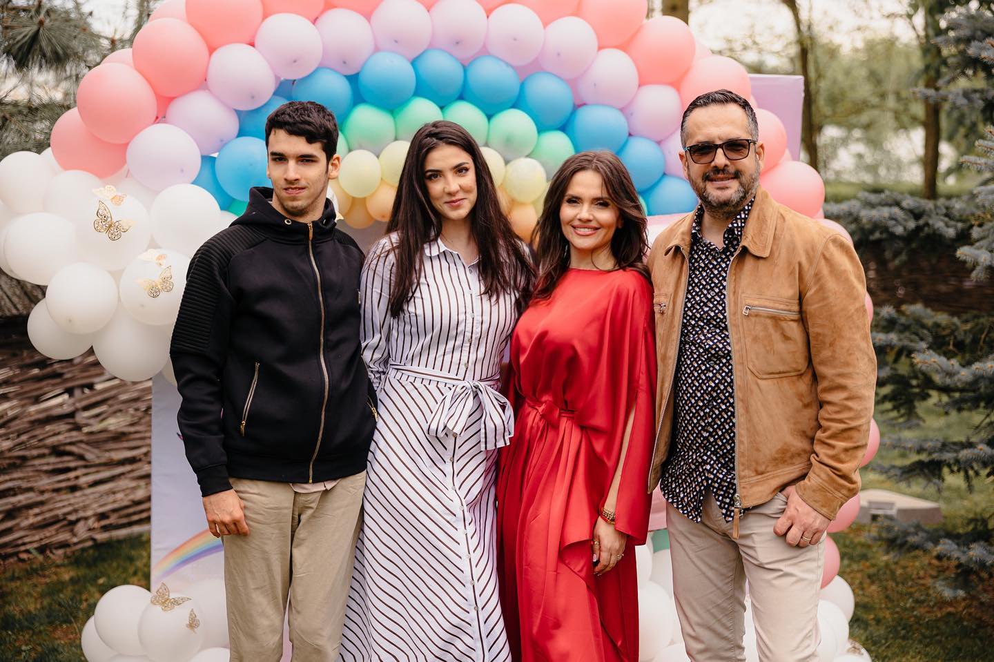 Cristina Șișcanu și Mădălin Ionescu la o petrecere, stând lângă un panou foto, alături de copiii pe care acesta îi are din prima căsnicie