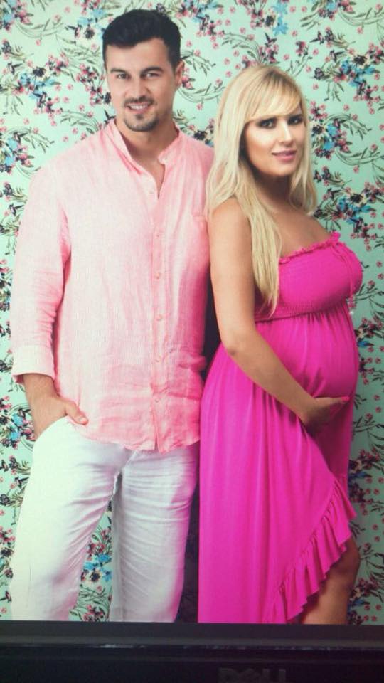 Adrian Alexandrov îmbrăcat în pantaloni albi și cămașă roz, alături de Elena Udrea, pe vremea când aceasta era însărcinată cu fiica lor, Eva, îmbrăcată în rochie roz