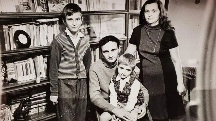 Imagine alb-negru cu Raisa Vieru și Grigore Vieru alături de cei doi copii ai lor, așezați lângă o bibliotecă