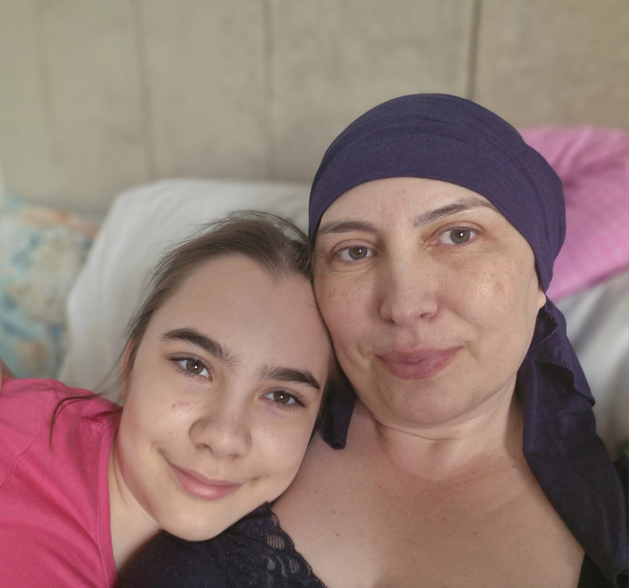 Mirela Petcu Ecobici stând în pat, alături de fiica ei, în ultimele clipe din viață, purtând o eșarfă pe cap