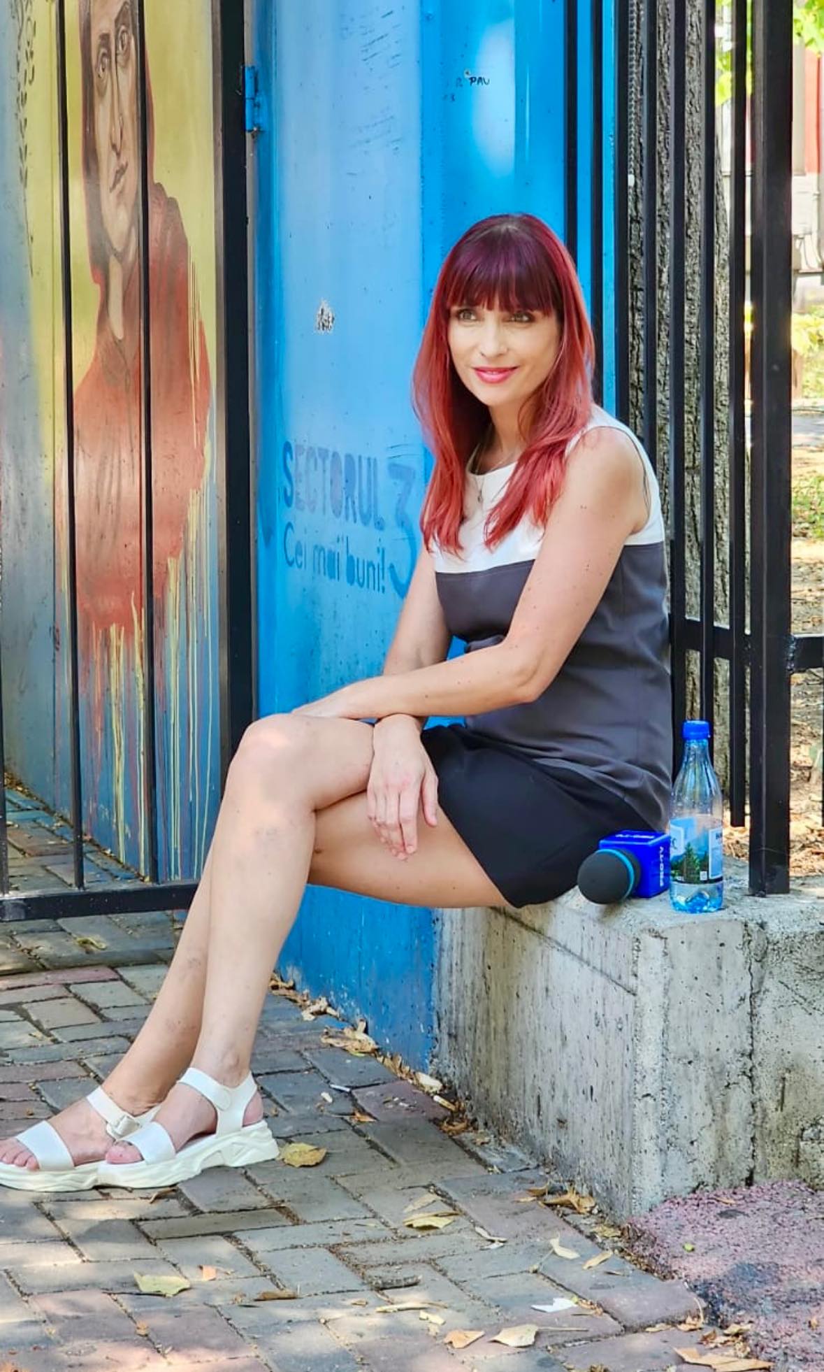 Adriana Stere, corespondenta Știrilor Pro TV, stâns pe trotuat, așezată pe marginea unui gard, în timpul muncii de teren