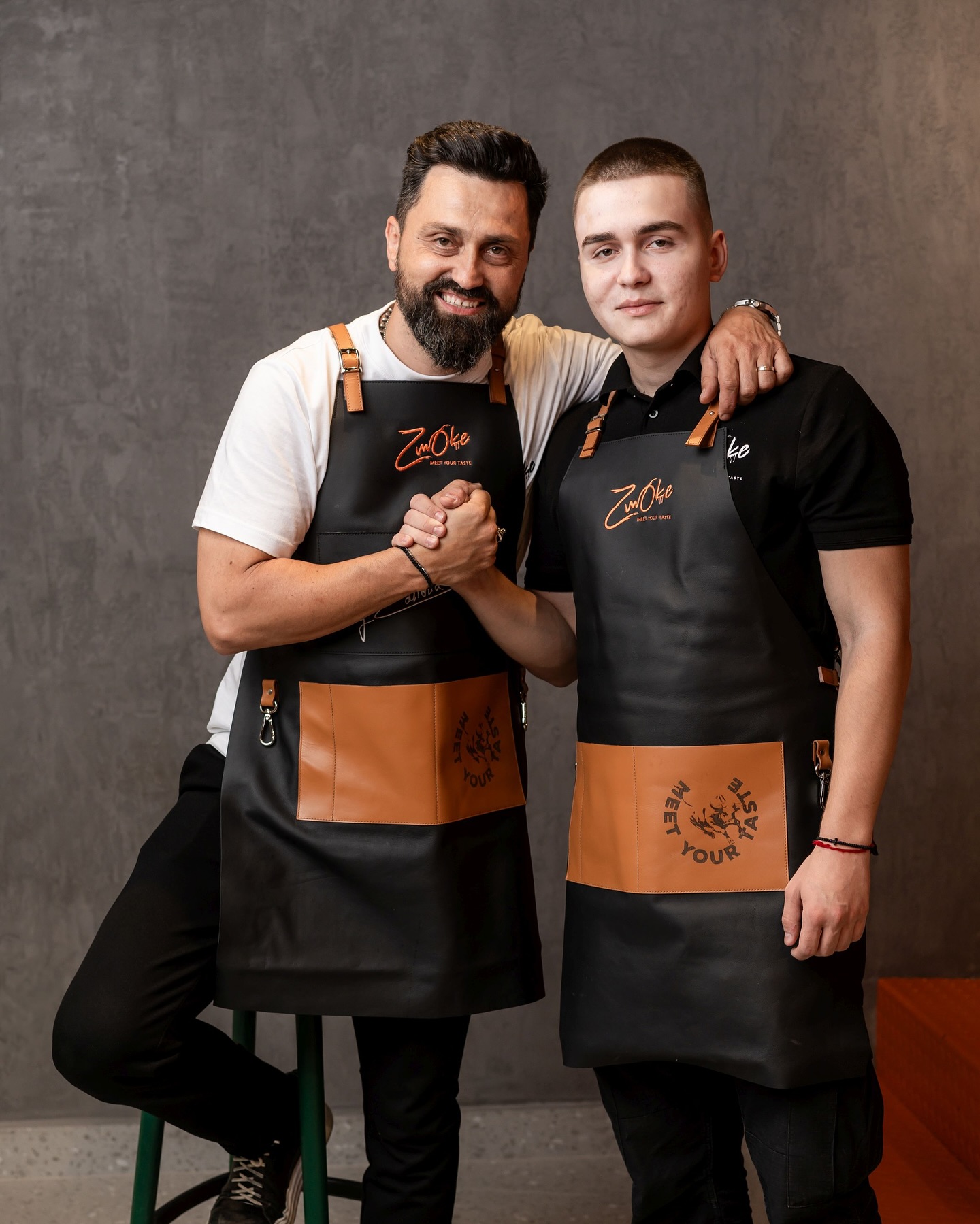 Orlando Zaharia dând mâna cu fiul lui Andreas, îmbrăcați amândoi cu hainele de muncă, pe care le poartă la noul lor restaurant.