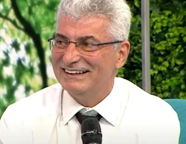 Silviu Prigoană zâmbitor într-o emisiune TV, cu microfonul în mână