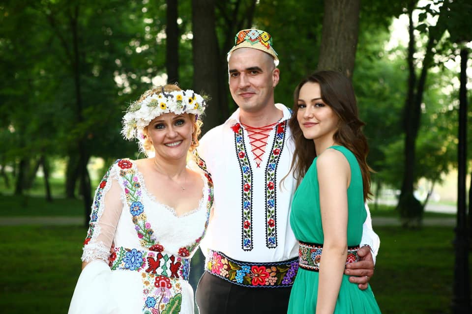 Elena Lasconi și soțul ei îmbrăcați în costum popular, îmbrățișându-se cu fiica ei din prima căsnicie, Oana Lasconi, îmbrăcată într-o rochie verde