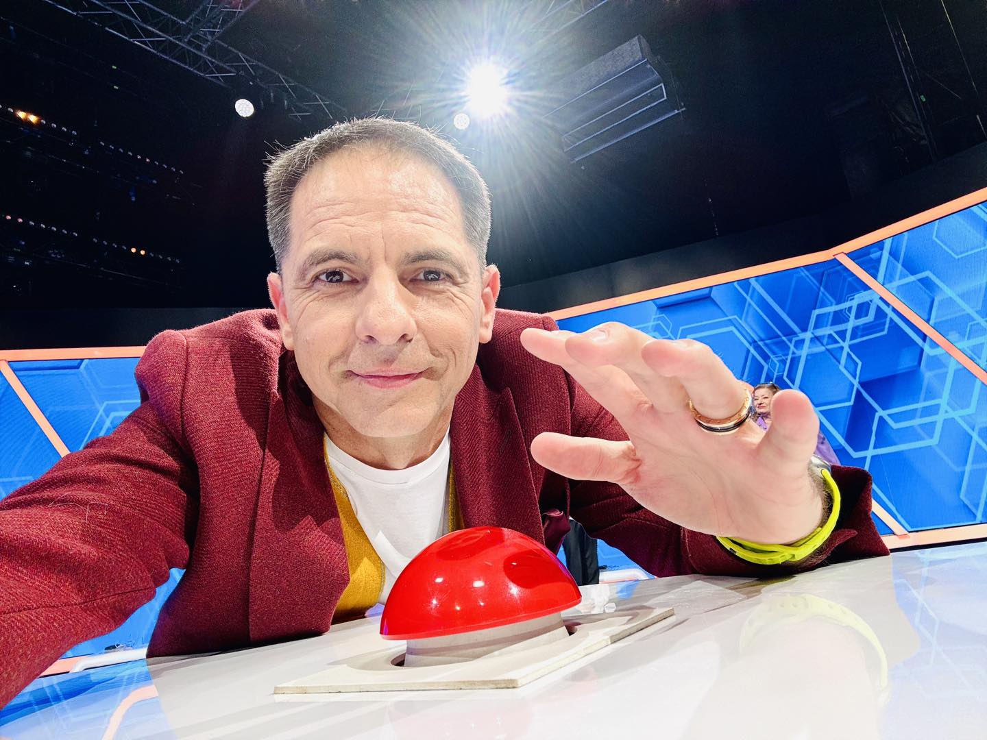 Dan Negru în platoul emisiunii „Jocul cuvintelor”, simulând apăsarea butonului pe care îl folosesc concurenții pentru a da soluția corectă în quiz show