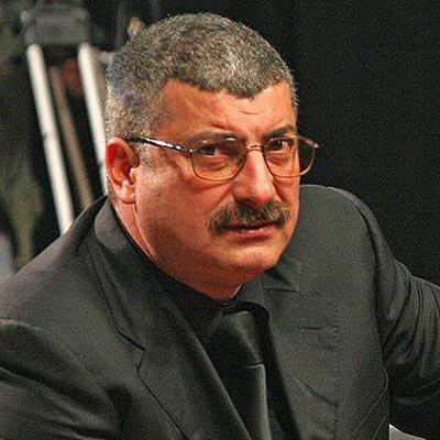 Silviu Prigoană îmbrăcat într-un costum negru, cu cămașă neagră și cravată de aceeași culoare, purtând ochelari de vedere