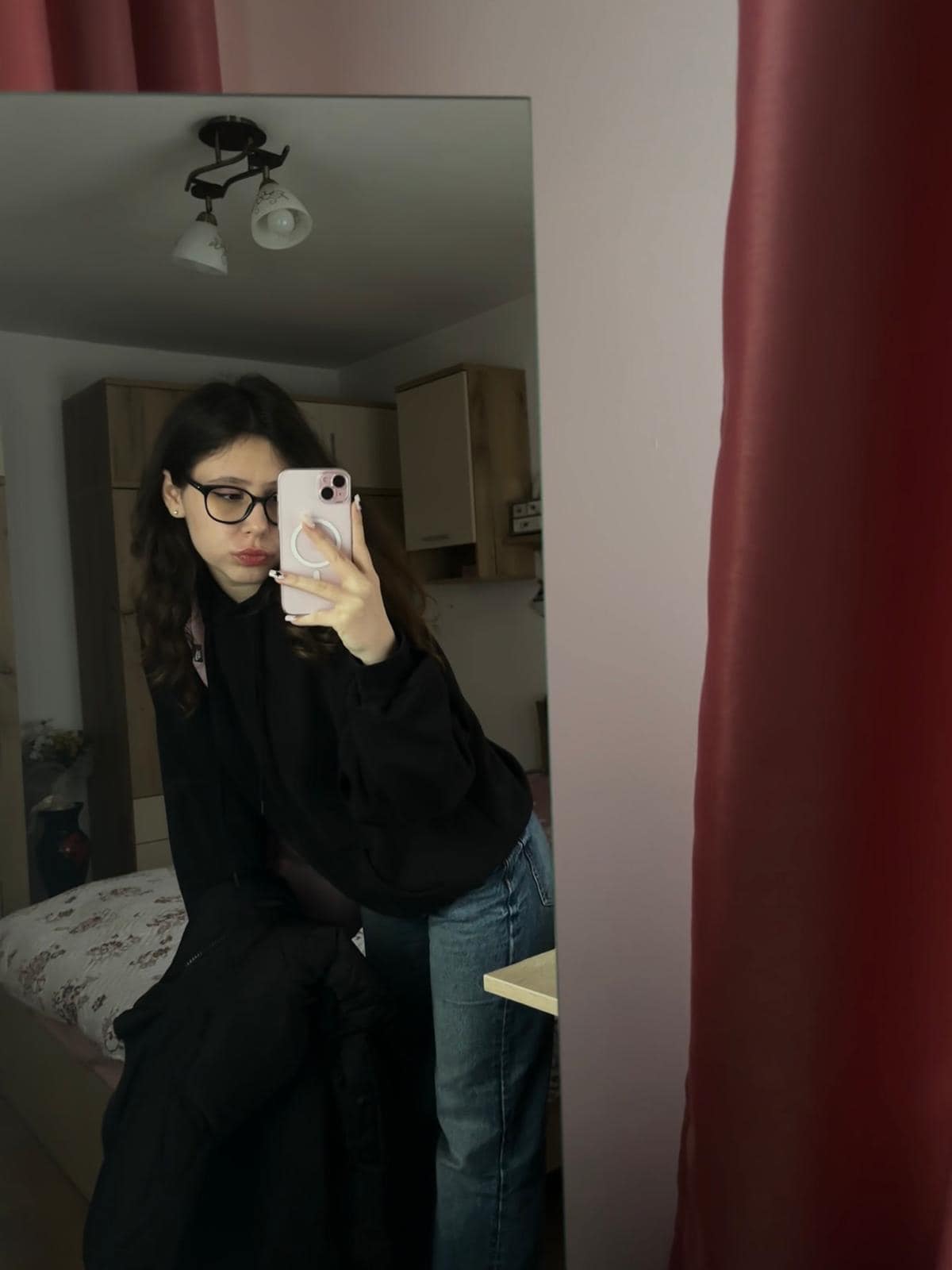 Cătălina Toma făcându-și o fotografie în oglindă, îmbrăcată în jeanși albaștri și bluză neagră