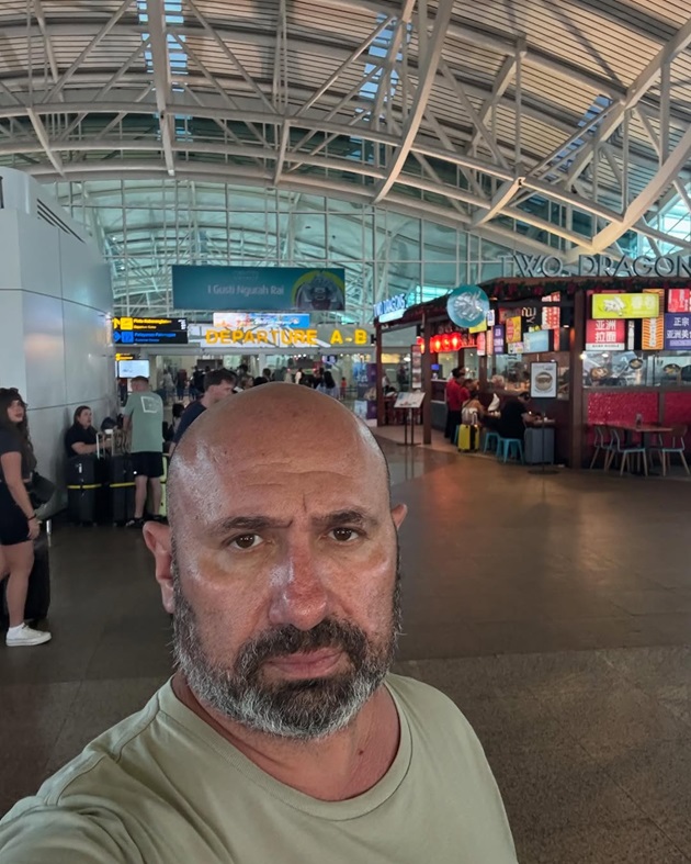 Cătălin Scărlătescu făcându-și un selfie în aeroportul din Bali, îmbrăcat într-un tricou vernil