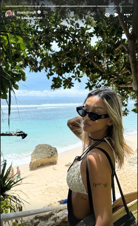 Nadd Hu pe plajă, în Bali, trecându-și mâna prin păr