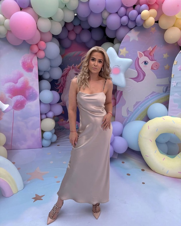 Elena Vîșcu lângă photo cornerul de la o petrecere pentru copii, îmbrăcată în rochie lungă cu bretele