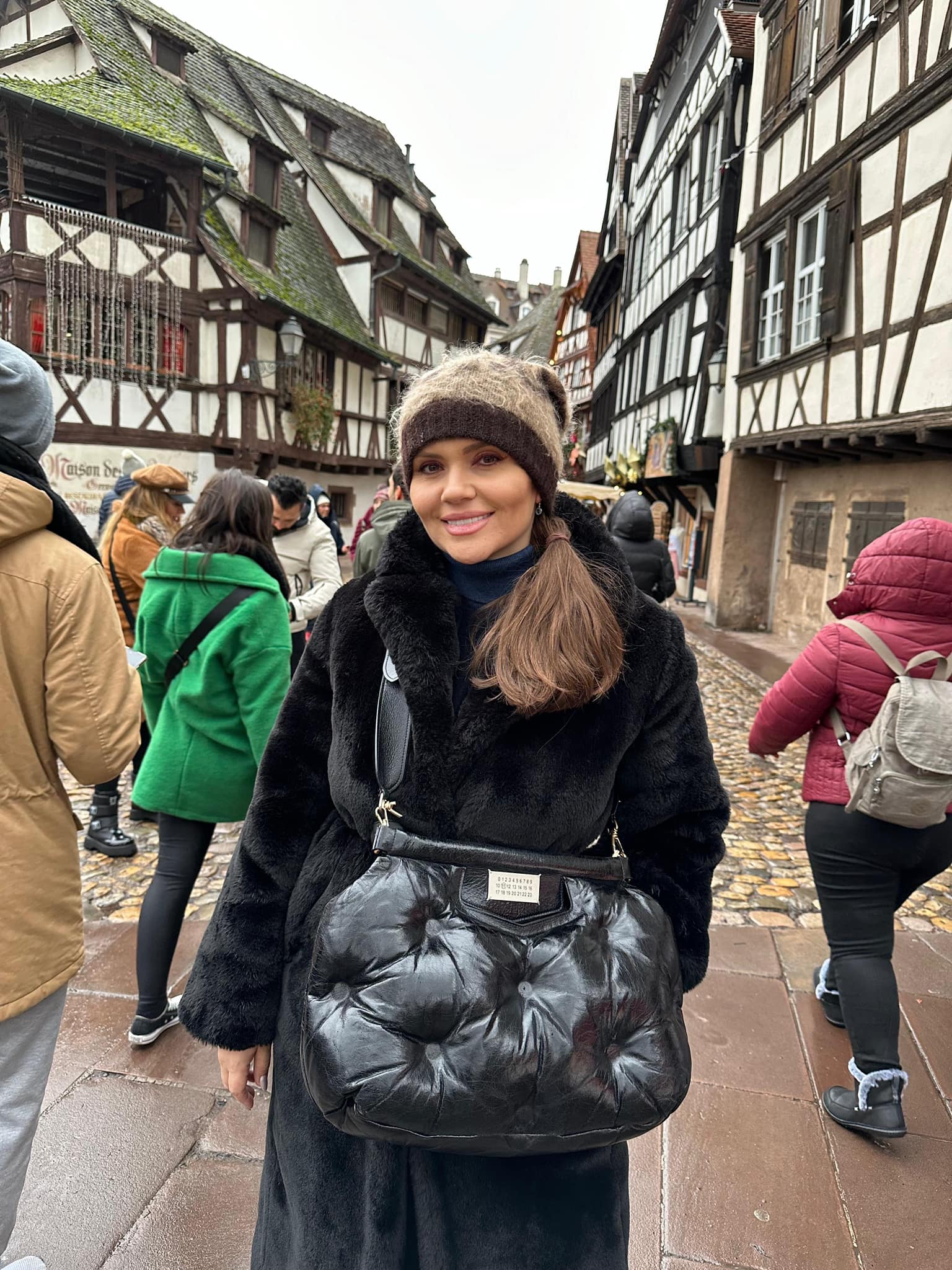 Cristina Șișcanu în vacanță, îmbrăcată într-un palton gros de blană, cu căciulă pe cap și cu o geantă mare tip poștaș pe umăr