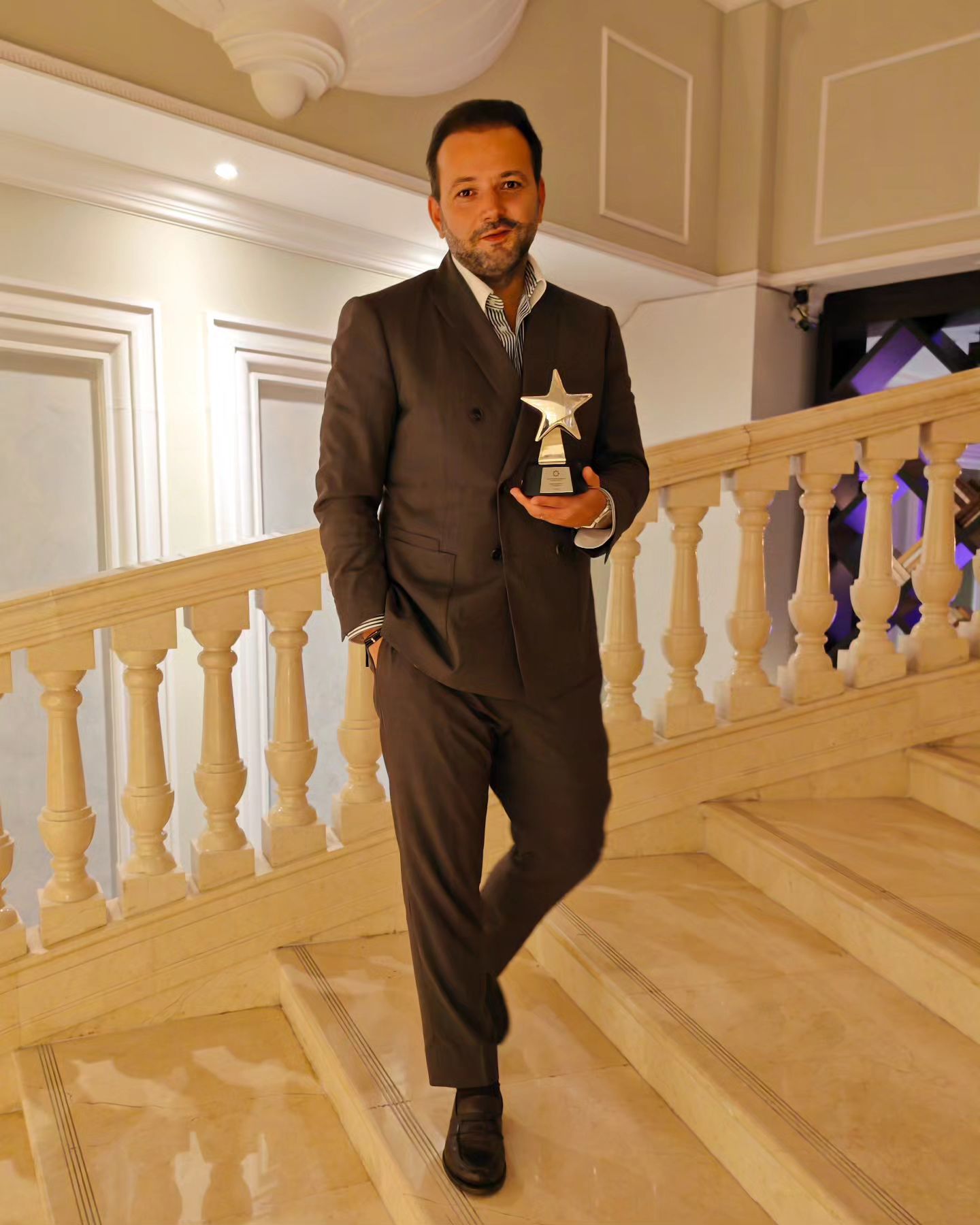 Mihai Morar stând pe o scară de marmură, îmbrăcat în costum, la Romanian Influencer Awards