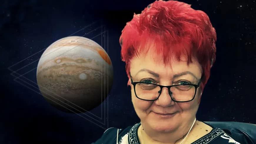 Gabriela Dima, cunoscută drept Minerva, zâmbitoare, cu părul roșcat și ochelarii la ochi