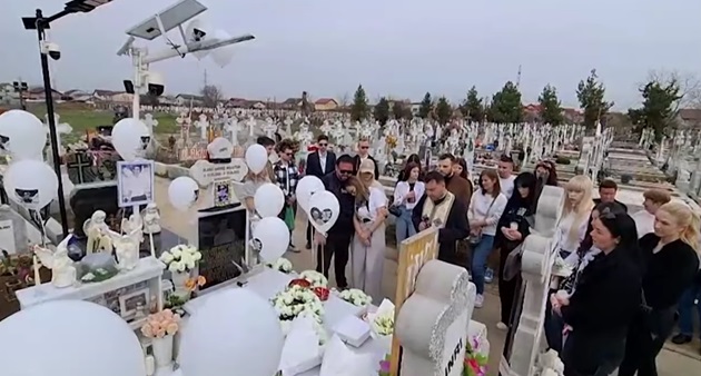 Oamenii prezenți la comemorarea lui Sebastian Olariu, în cimitir, cu baloane albe și flori albe