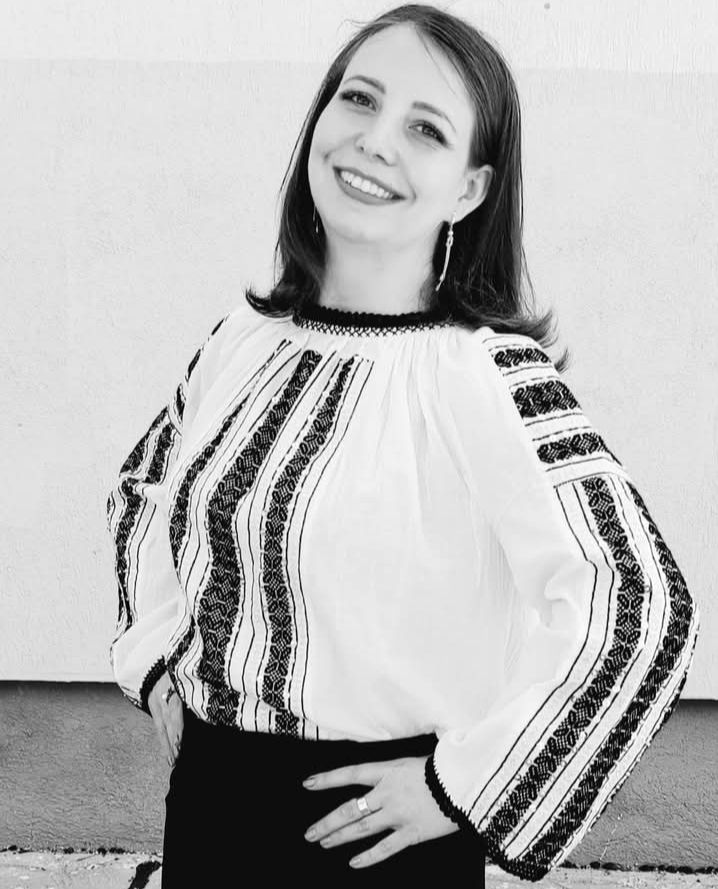 Imagine alb-negru cu Ioana Roșu zâmbitoare, îmbrăcată în ie și fustă neagră