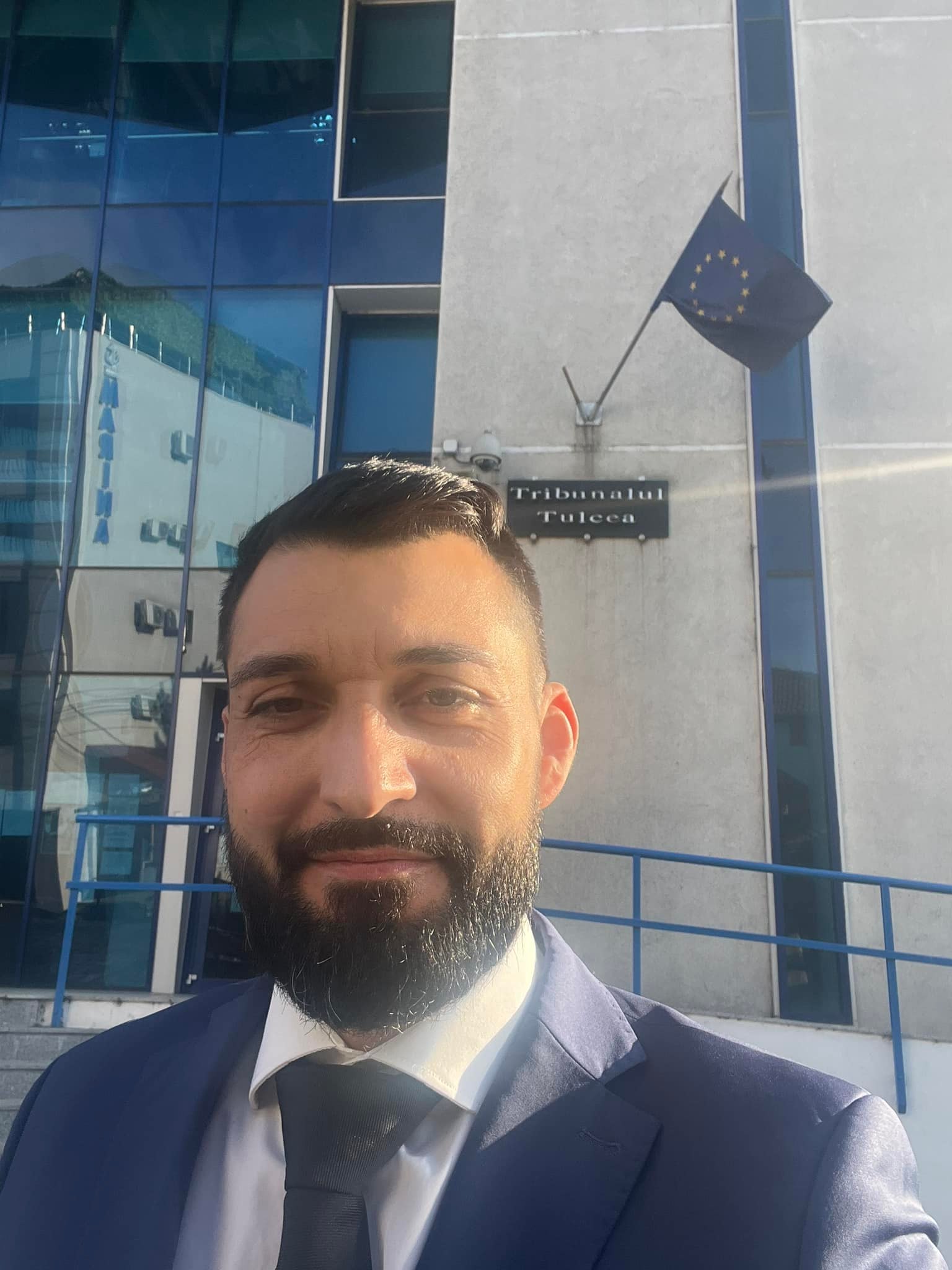 Cristian Porneală în costum albastru închis, făcându-și un selfie în fața Tribunalului Tulcea