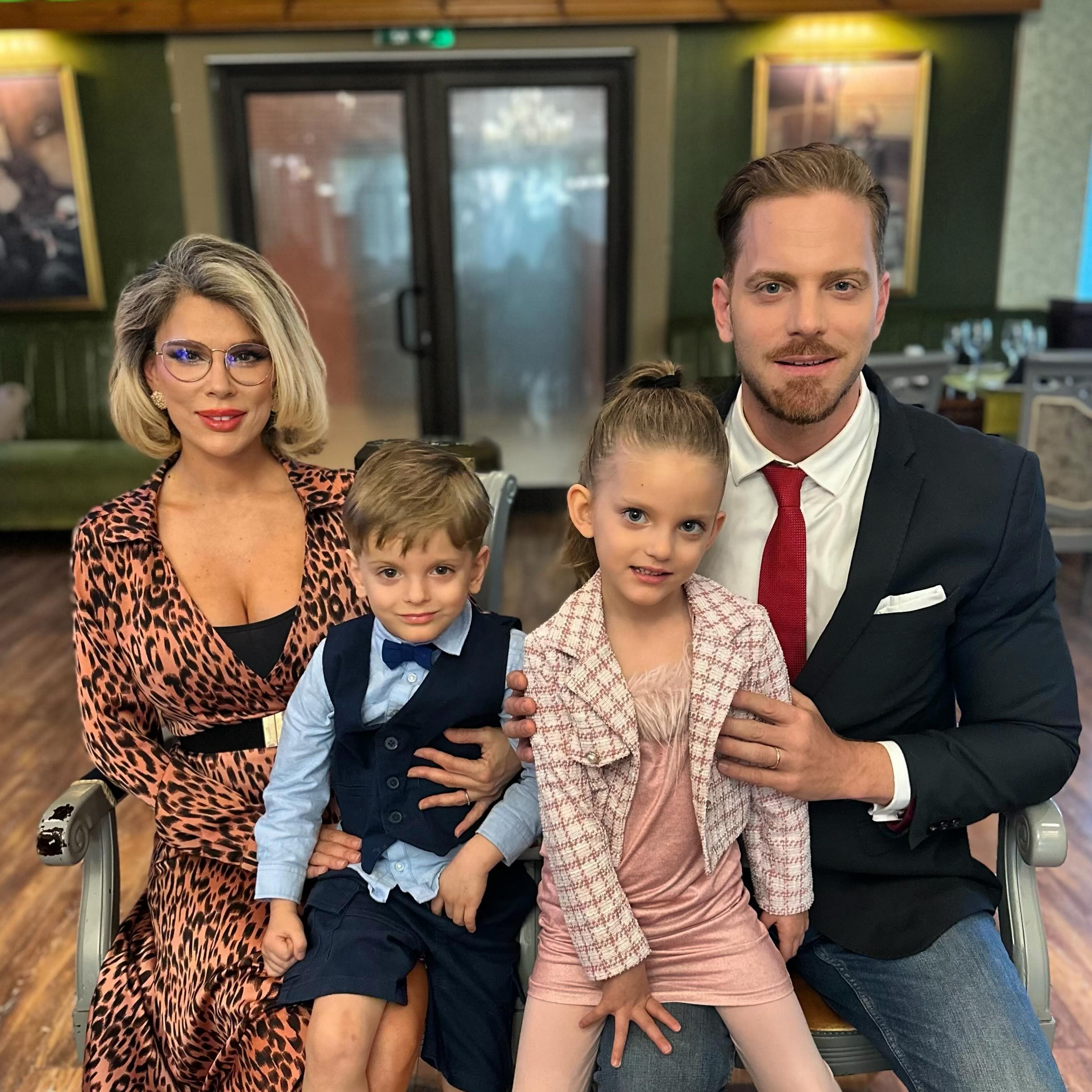 Alina Laufer și Ilan Laufer stând pe două scaune alăturate și ținându-și gemenii pe picioare