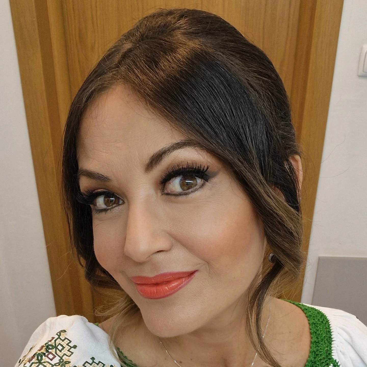 Anca Țurcașiu cu părul prins, îmbrăcată într-o ie albă cu motive tradiționale verzi