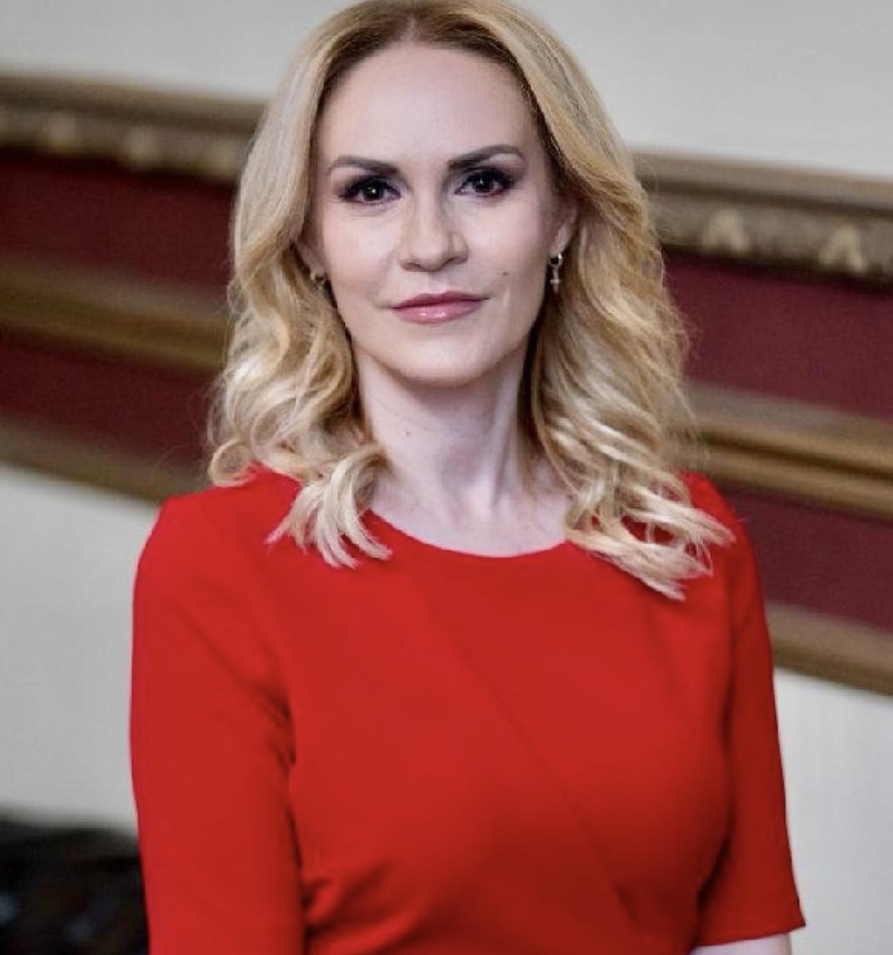 Gabriela Firea îmbrăcată în roșu, cu bărul împărțit în două de o cărare