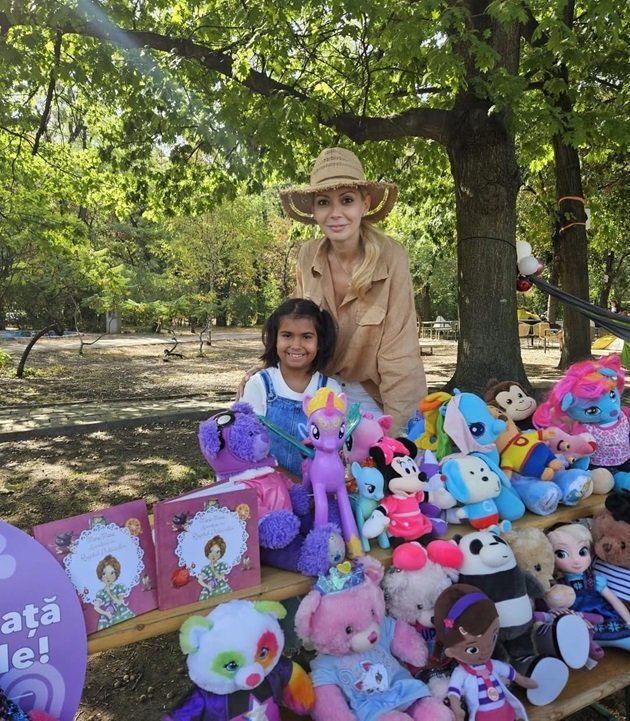 Daciana Sârbu alături de Maria, fetița pe care a adoptat-o împreună cu Victor Ponta, stând în parc, în spatele unei bănci pline cu jucării și cărți