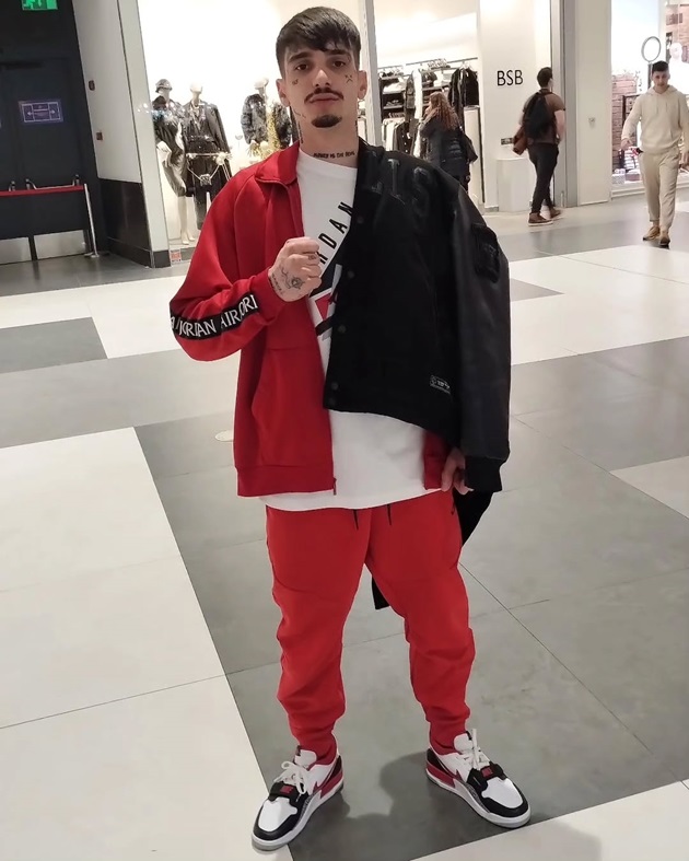 Trapperul Raul WS într-un mall, îmbrăcat într-un trening roșu și ținând pe umăr o jachetă neagră