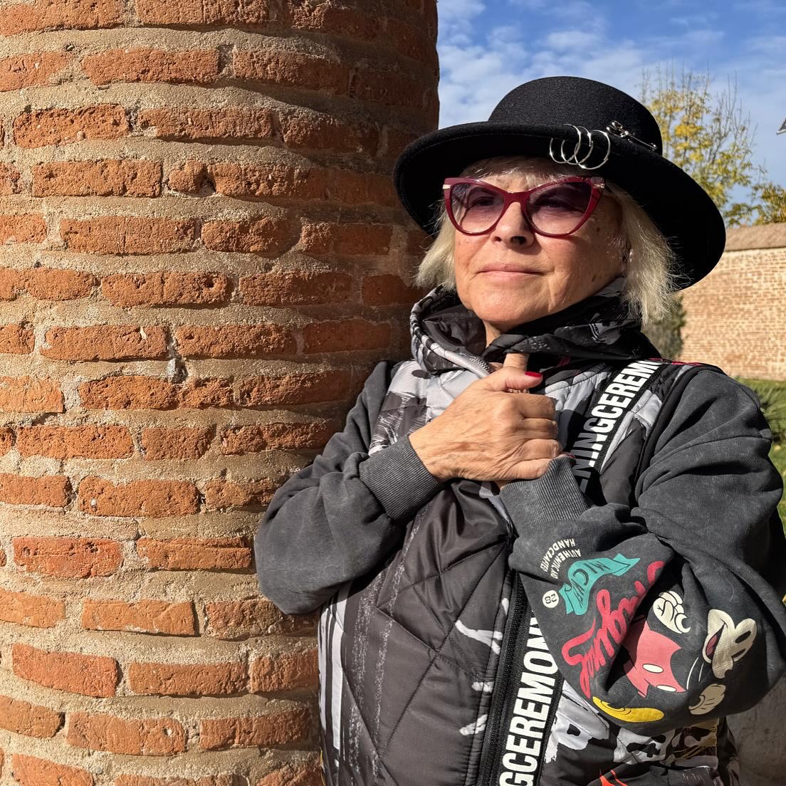 Mirabela Dauer îmbrăcată gros, cu pălărie pe cap și ochelari de soare la ochi, stând cu mâinile împreunate în jurul gâtului