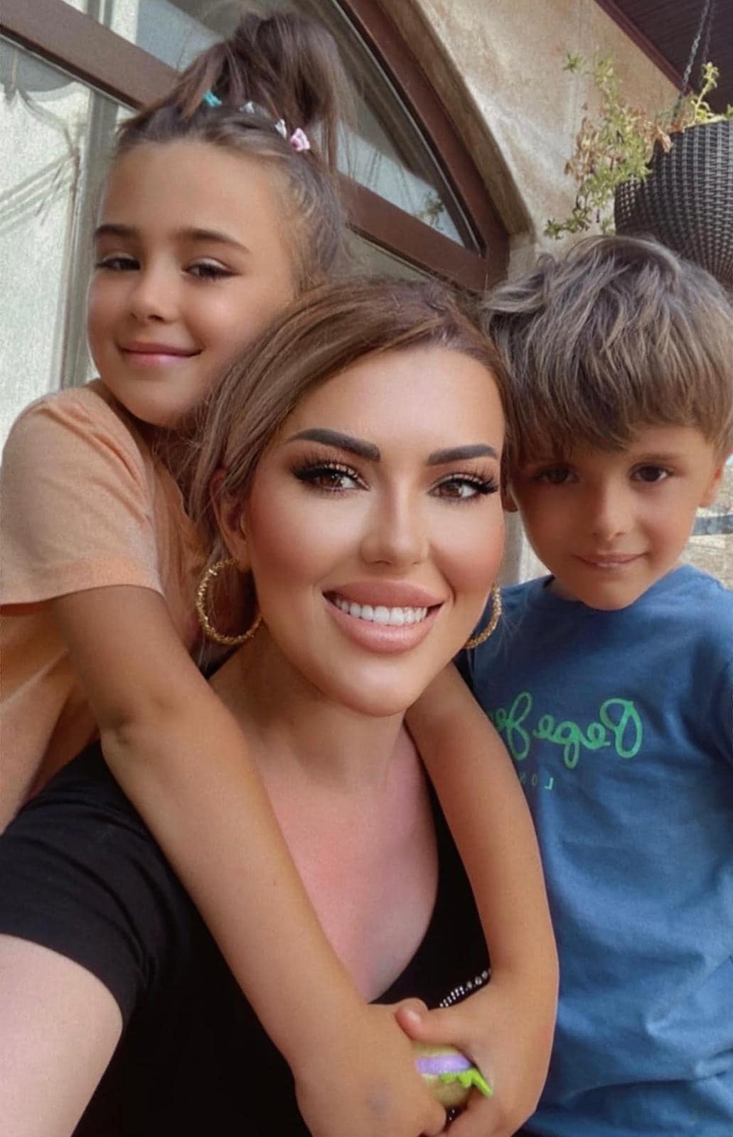 Iulia Sabbagh zâmbitoare, cuprinsă în brațe de fiica ei Anais, în timp ce lângă ele stă mezinul Geo