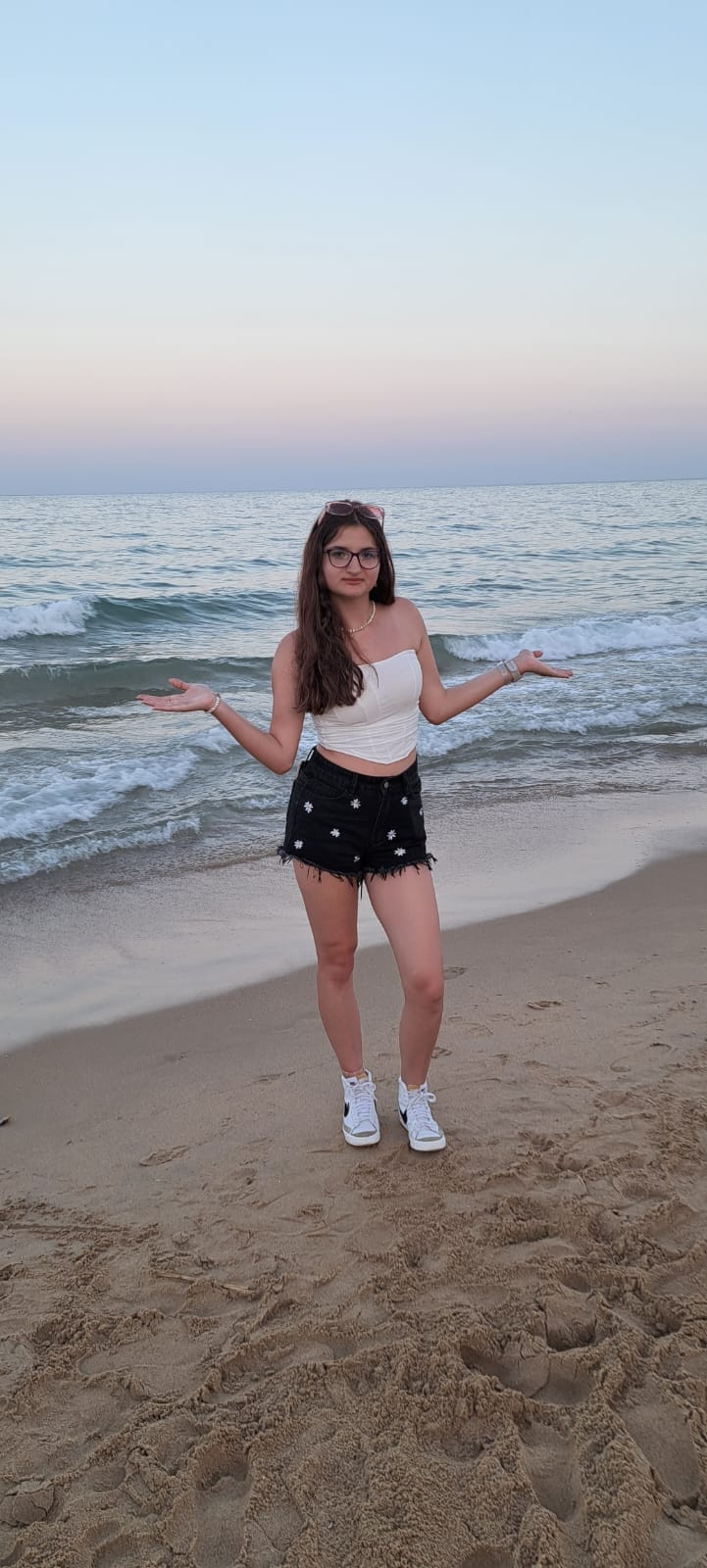 Iulia Barbu la mare, pe plajă, în pantaloni scurți, top alb fără bretele și teneși