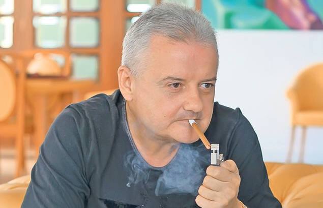 Irinel Columbeanu serios, aprinzându-și o țigară și evitând să privească spre obiectivul aparatului foto