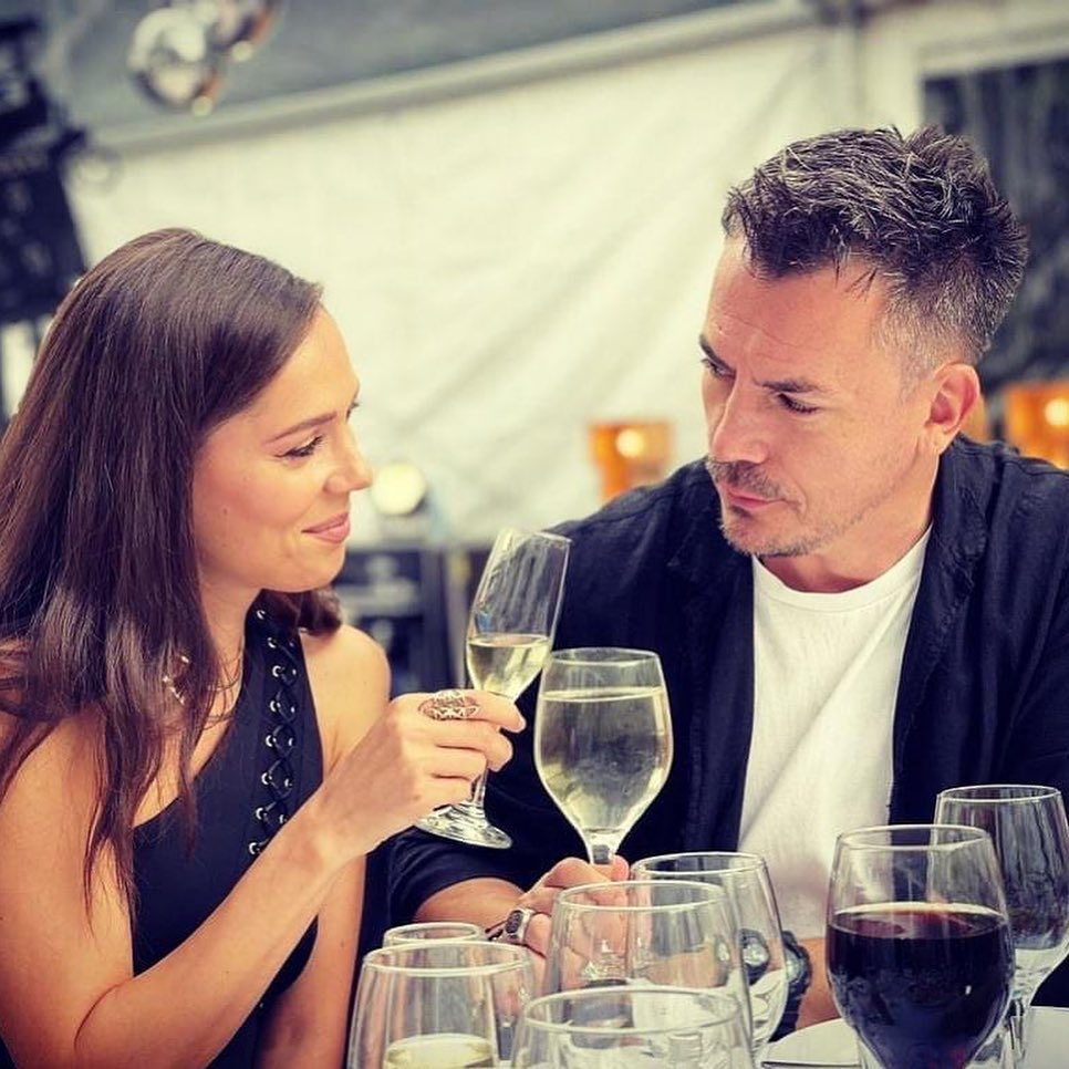 Răzvan Fodor și soția sa, Irina, stând la masă, ciocnind un pahar de vin și privindu-se în ochi