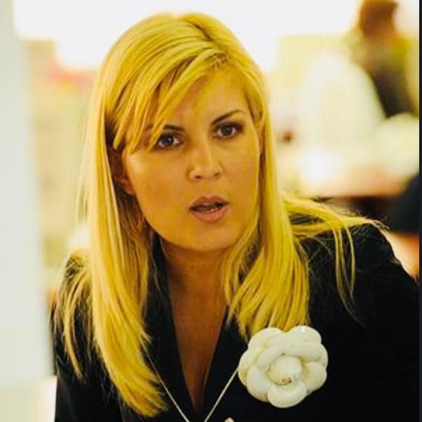 Elena Udrea îmbrăcată într-un sacou negru, cu o broșă mare, în formă de trandafir în piept