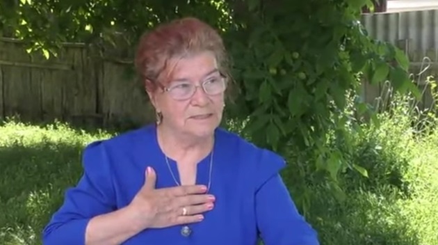 Ioana Păduraru Rusu, femeia care a luat BAC-ul la 75 de ani, într-un interviu în care vorbește despre experiența ei, îmbrăcată într-o bluză albastră și punându-și mâna în dreptul inimii