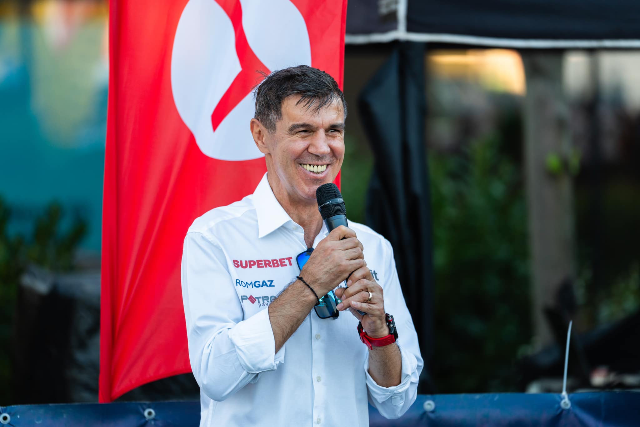 Mihai Leu zâmbitor, vorbind în fața celor prezenți la o cursă de mașini