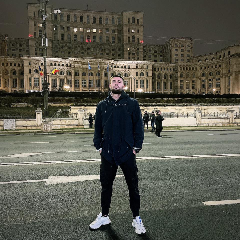 Ionuț Dogaru stând cu mâinile în buzunar în fața Casei Poporului