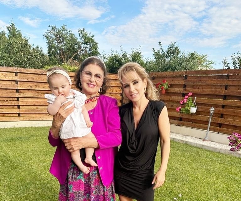 Irina Loghin ținând-o în brațe pe nepoata ei, stând alături lângă fiica ei și făcând o fotografie împreună