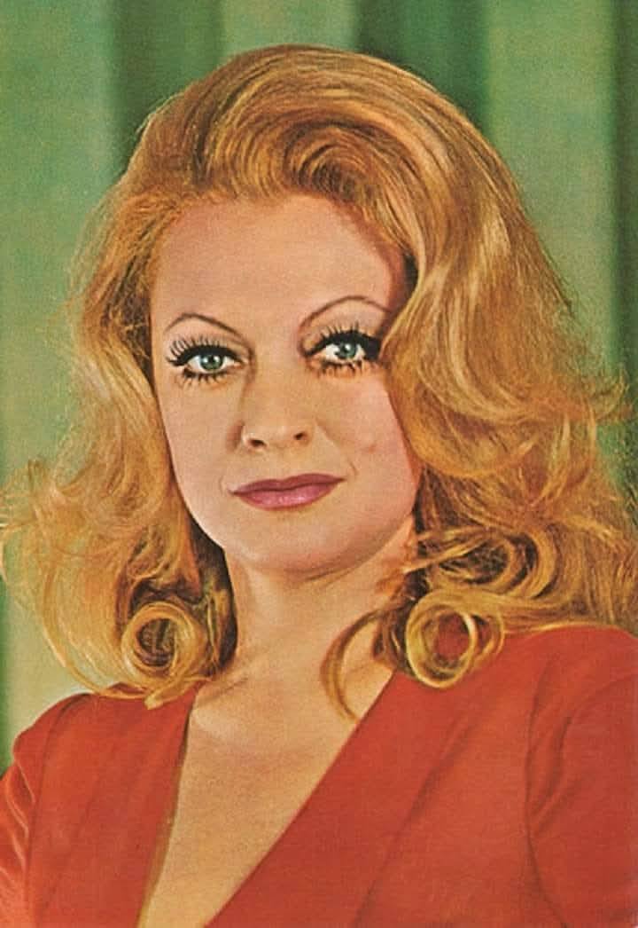 Actrița Ioana Bulcă în tinerețe, îmbrăcată într-un sacou roșu, cu părul blond și ondulat