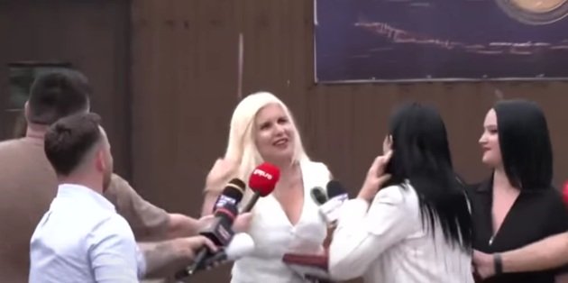 Elena Udrea îmbrăcată într-un costum alb, zâmbitoare și proaspăt vopsită, înconjurată de jurnaliști, în ziua eliberării