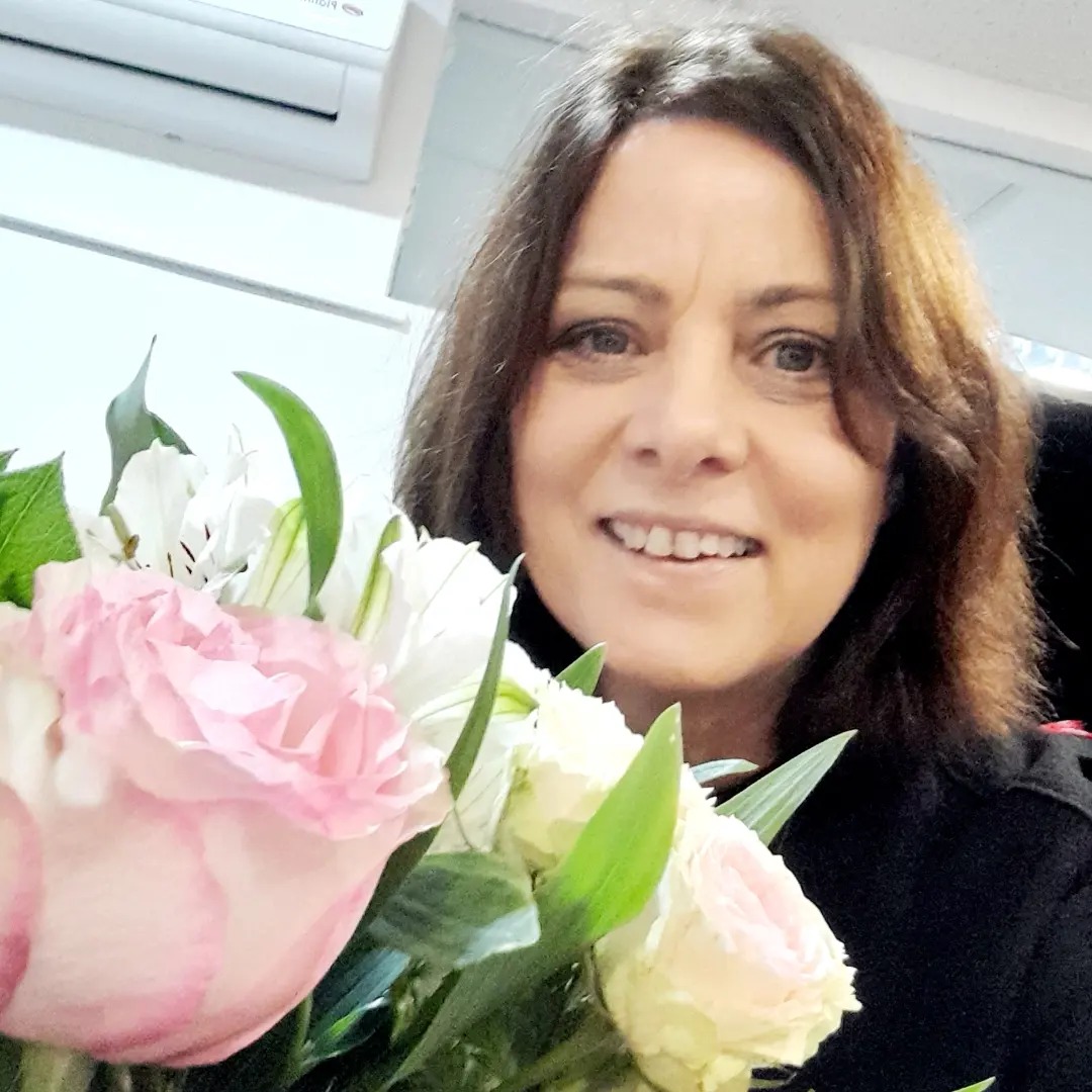 Lucia Efrim zâmbitoare, în 2024, în ziua în care a împlinit 56 de ani, ținând în mână un buchet de flori