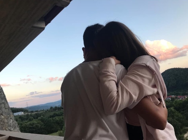 Ștefan și Ștefania stând împreună pe balcon, îmbrățișați, privind apusul