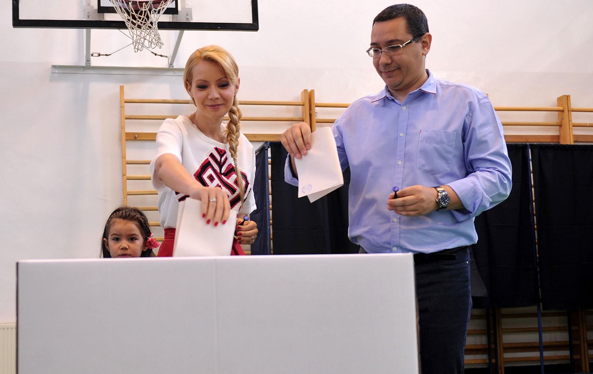 Victor Ponta și Daciana Sârbu zâmbitori, în secția de votare, introducând buletinele de vot în urnă, în anul 2014