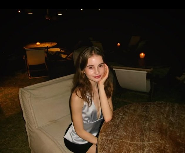 Irina Columbeanu stând la masă, pe o terasă, la ceas de seară