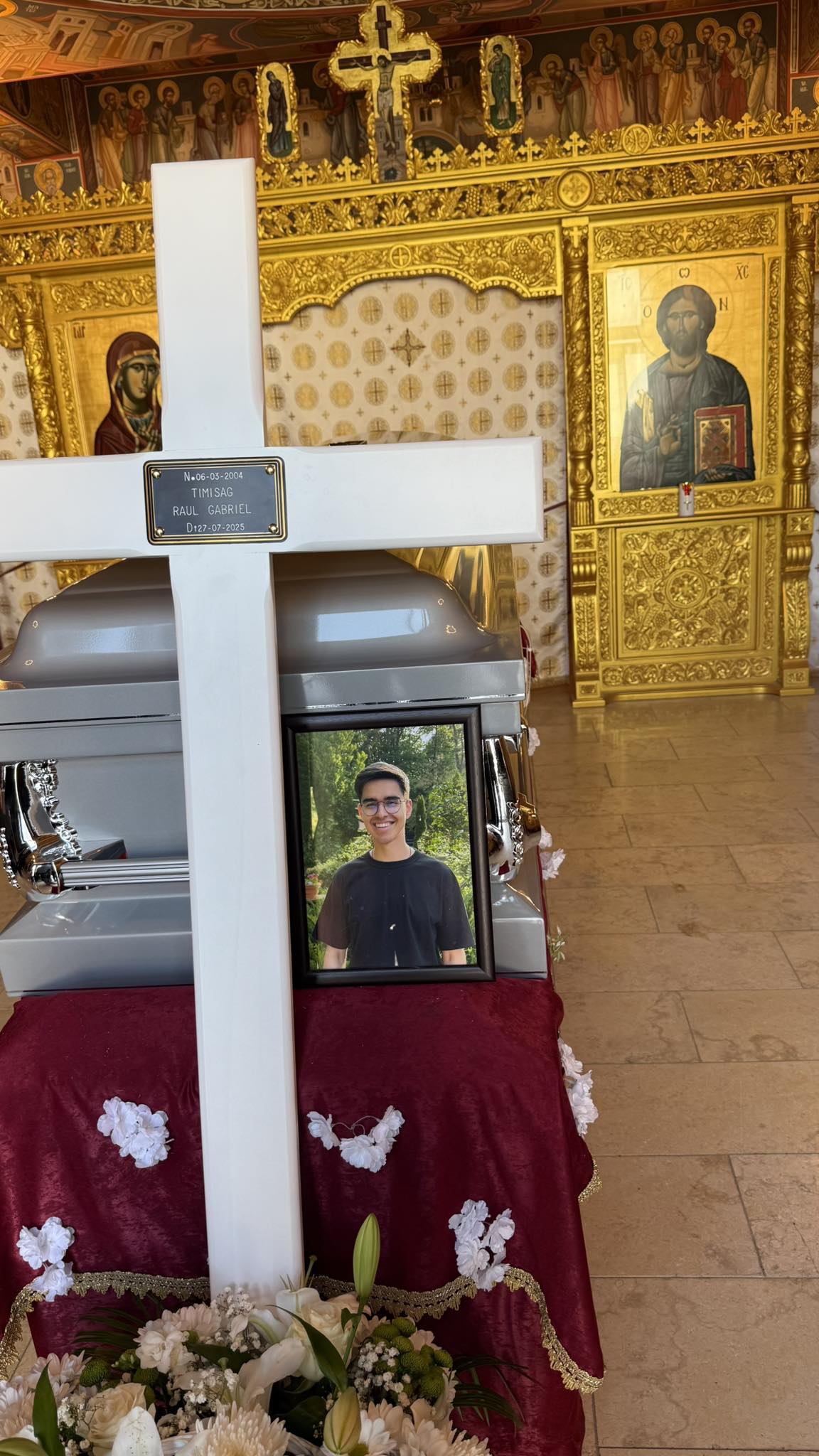 Sicriul lui Raul Gabriel Timișag, tânărul de 21 de ani care și-a pierdut viața în Statele Unite, cu o cruce albă lângă el, în biserică
