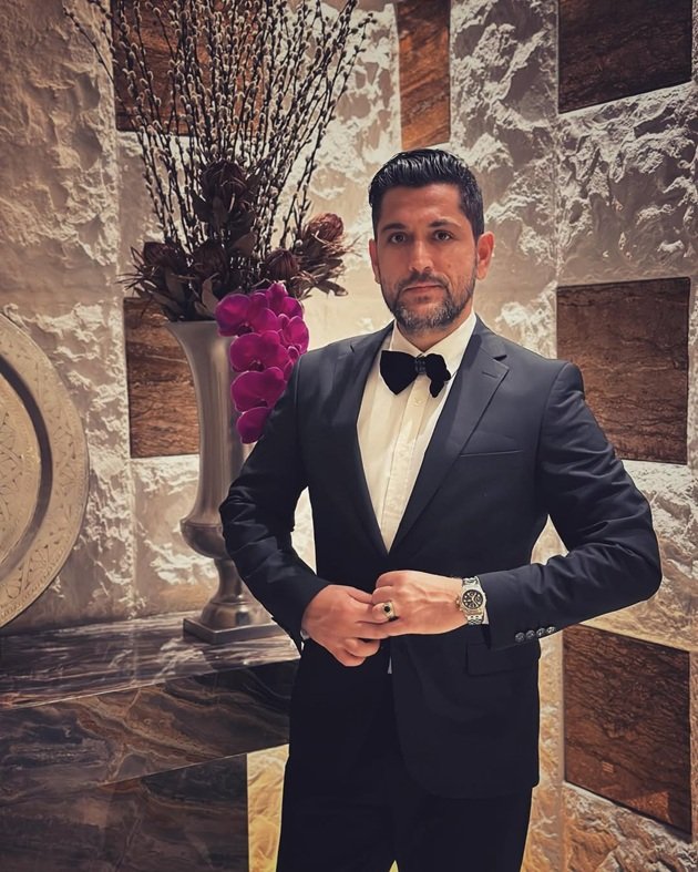 Cezar Ouatu elegant, cu părul dat pe spate, în costum negru, cu cămașă albă și papion negru, așezându-și sacoul