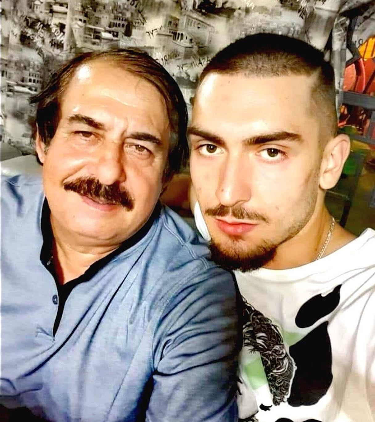 Cristian Botgros într-un tricou alb cu negru, cu lanț la gât, făcându-și un selfie alături de bunicul său, Nicolae Botgros, îmbrăcat într-o bluză albastră